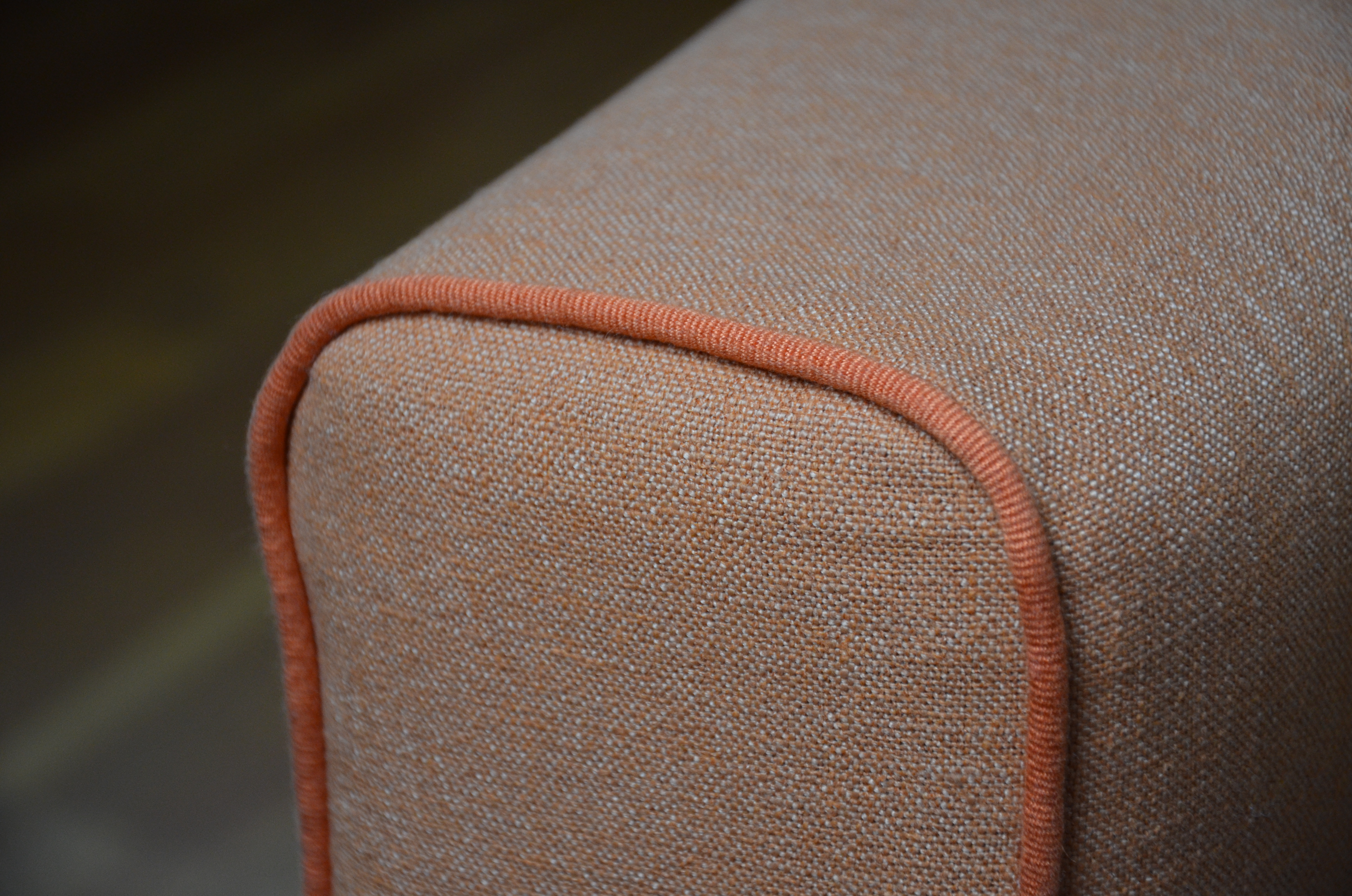 Real photograph of covered rounded piping continuing around a furniture corner. A general visible-profile example, not bag manufacture; internal cord, seam allowance and dimensions are not visible.