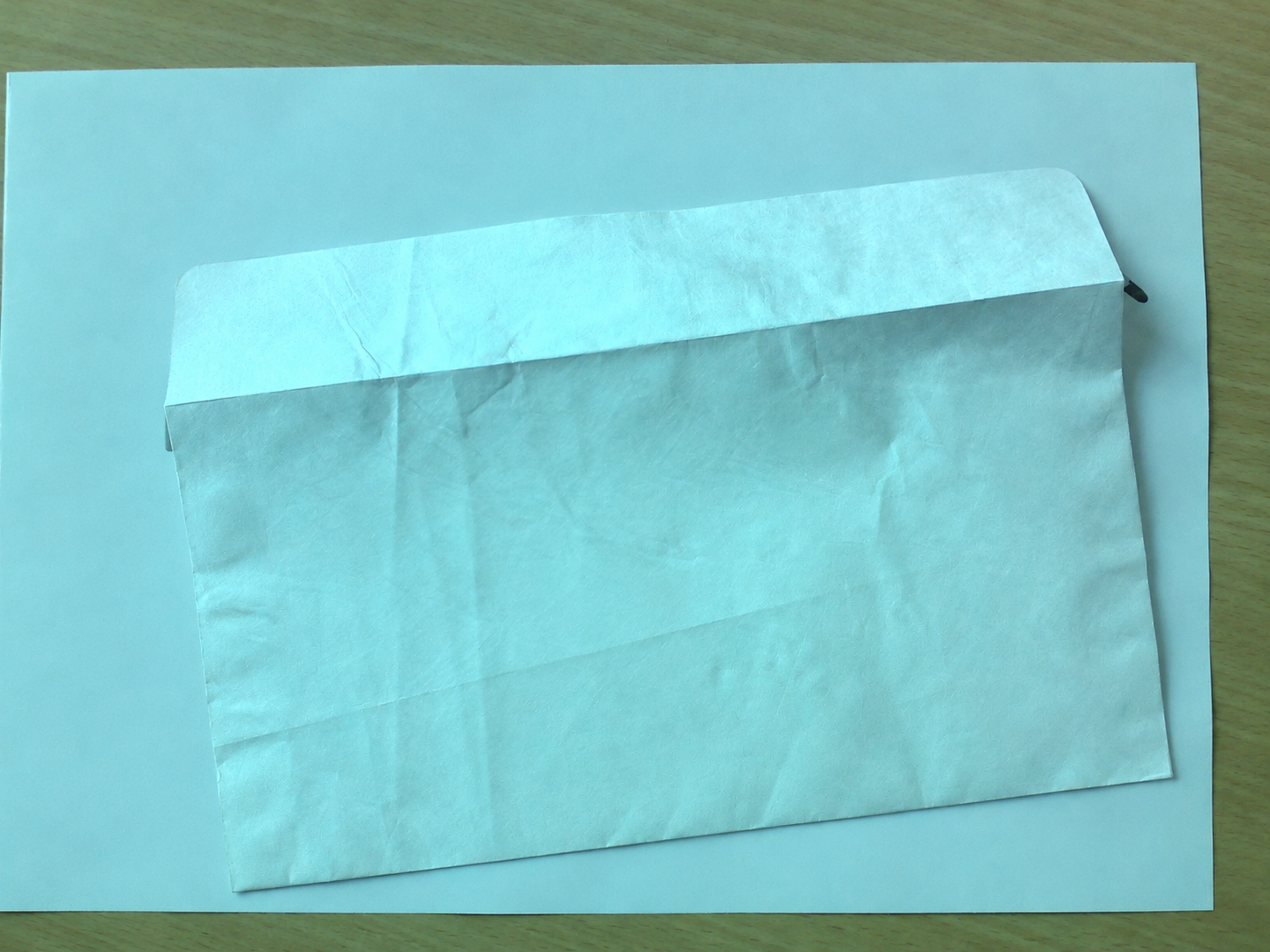 Real envelope photograph, identified by its source as Tyvek 1056D. Built-in image editing cleaned product logos, handwriting and background advertising while retaining the visible folded form. Edited areas are not microscopy or performance evidence. Not a JKPD bag sample; original and change record retained in the source package.