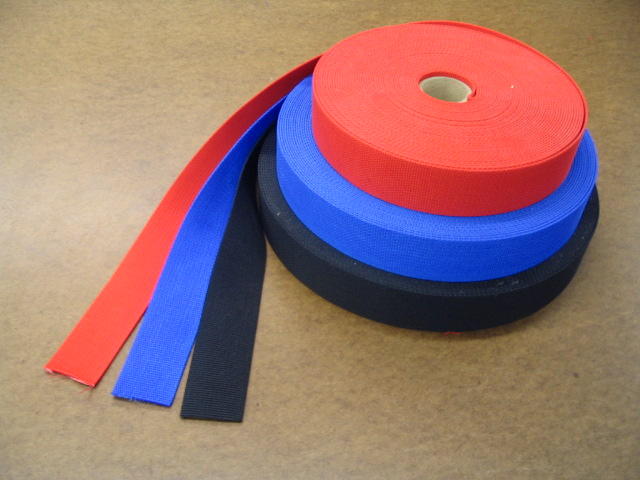Photograph of red, blue and black webbing rolls with loose lengths. Shows supplied form and edges; composition, dimensions and performance are not established. Not a JKPD product.