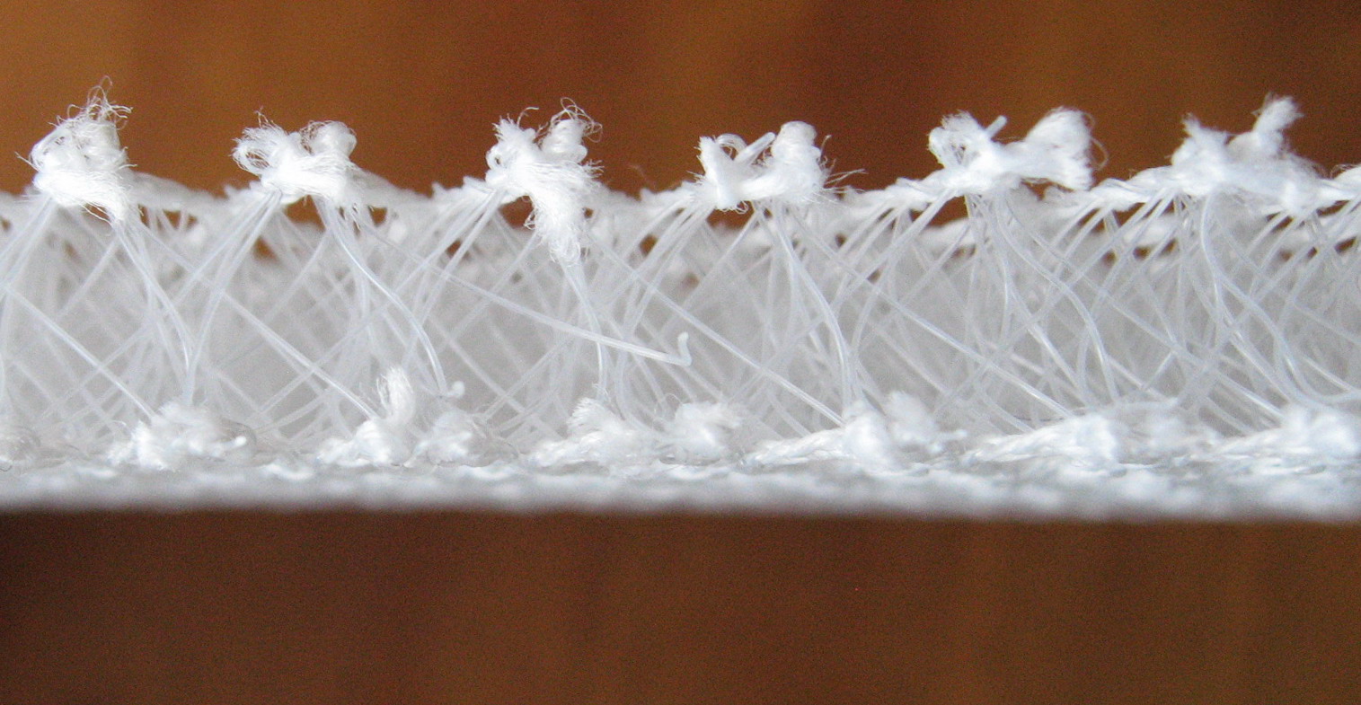 Real photograph of a spacer-fabric cross-section, showing connecting filaments and space between surfaces. Not a diagram; composition, article, thickness and compression performance are unverified. Not an identified manufacturer product discussed here.