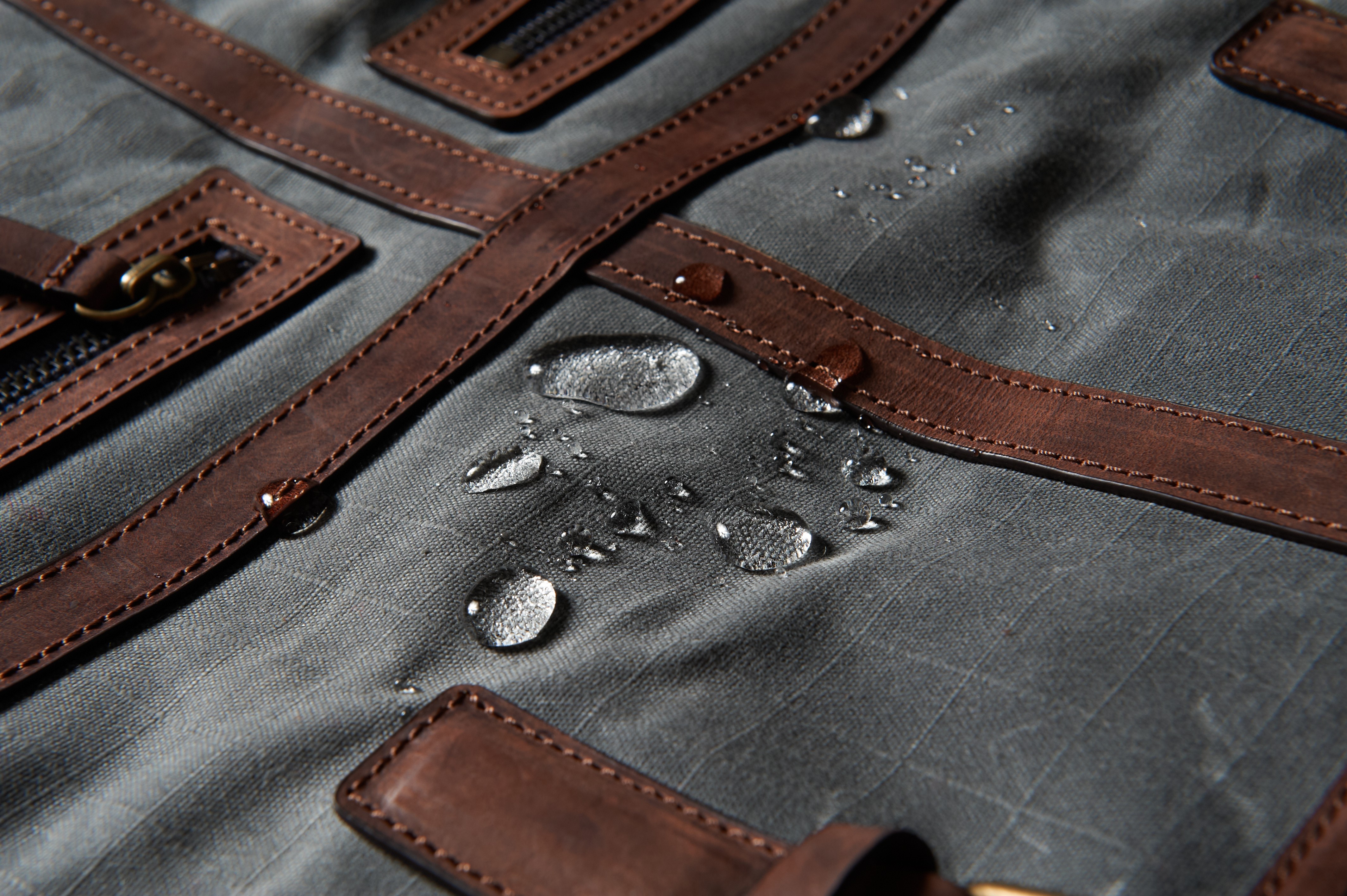 Real photograph of droplets on cloth and trim. Source author identifies Martexin waxed canvas; visible surface condition only. Weight, finish formulation, test conditions and finished-bag waterproofness are unverified. Not a JKPD case; unmodified.